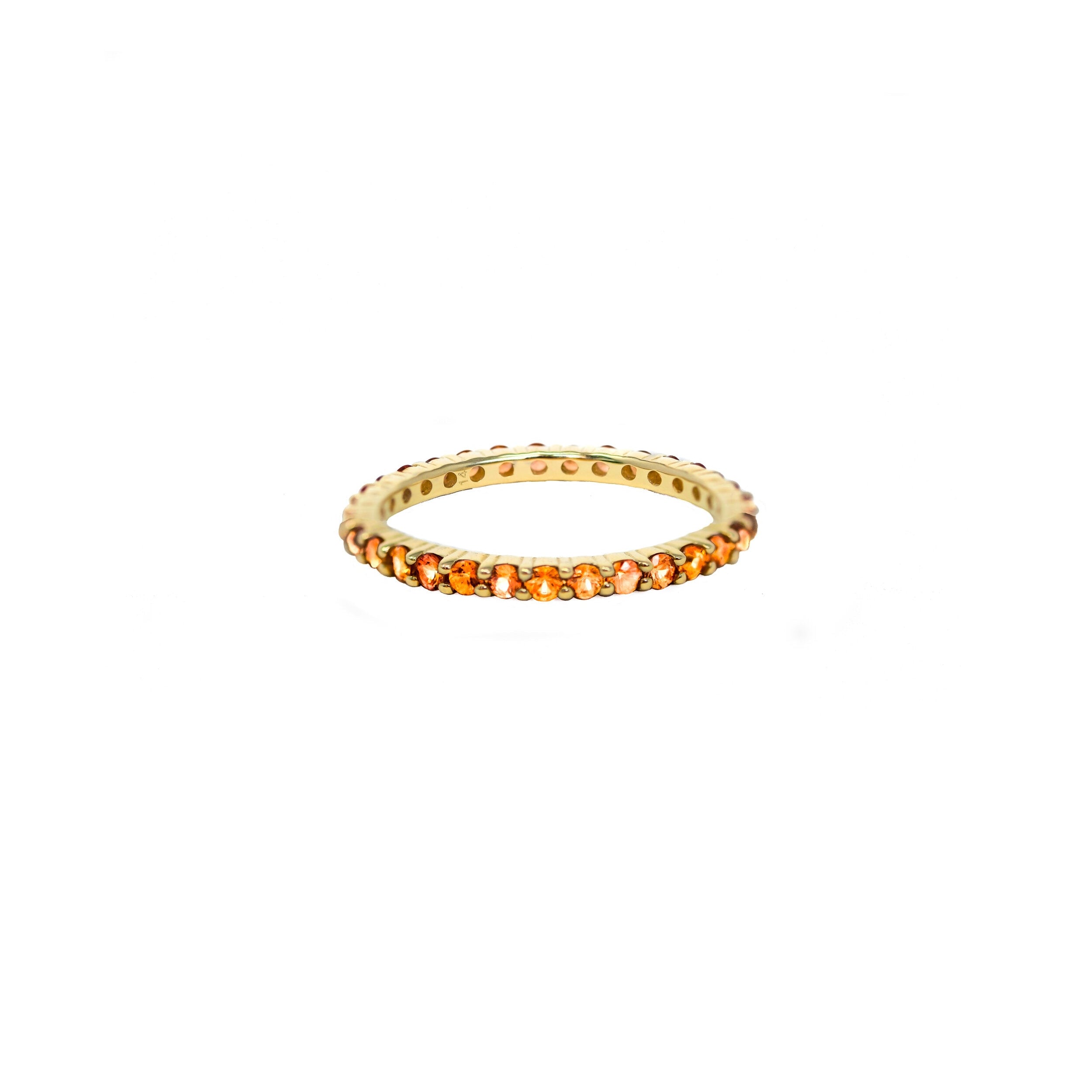 A 14K gold ring with a round cut orange sapphire centerpiece, designed for stacking.