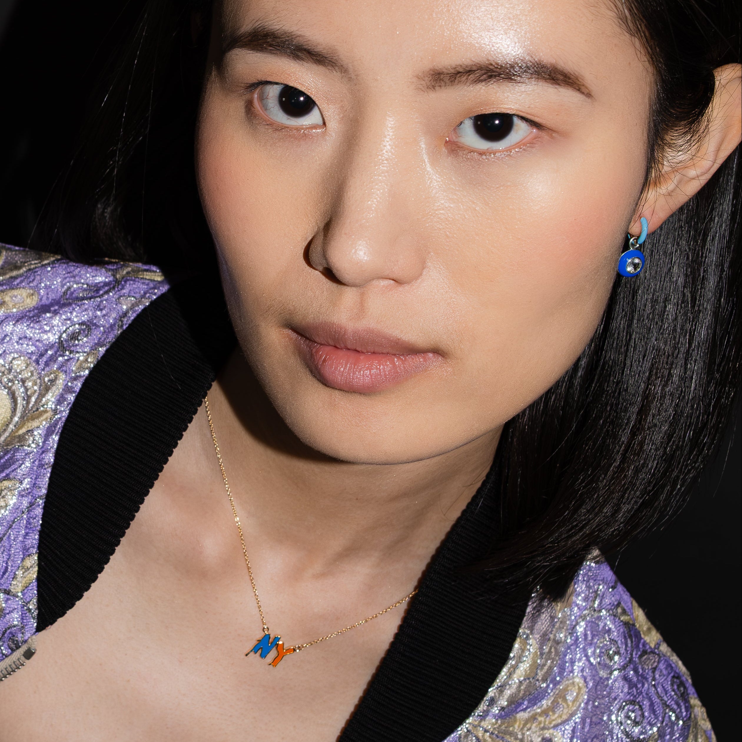 Person wearing a purple embroidered garment with a dark background