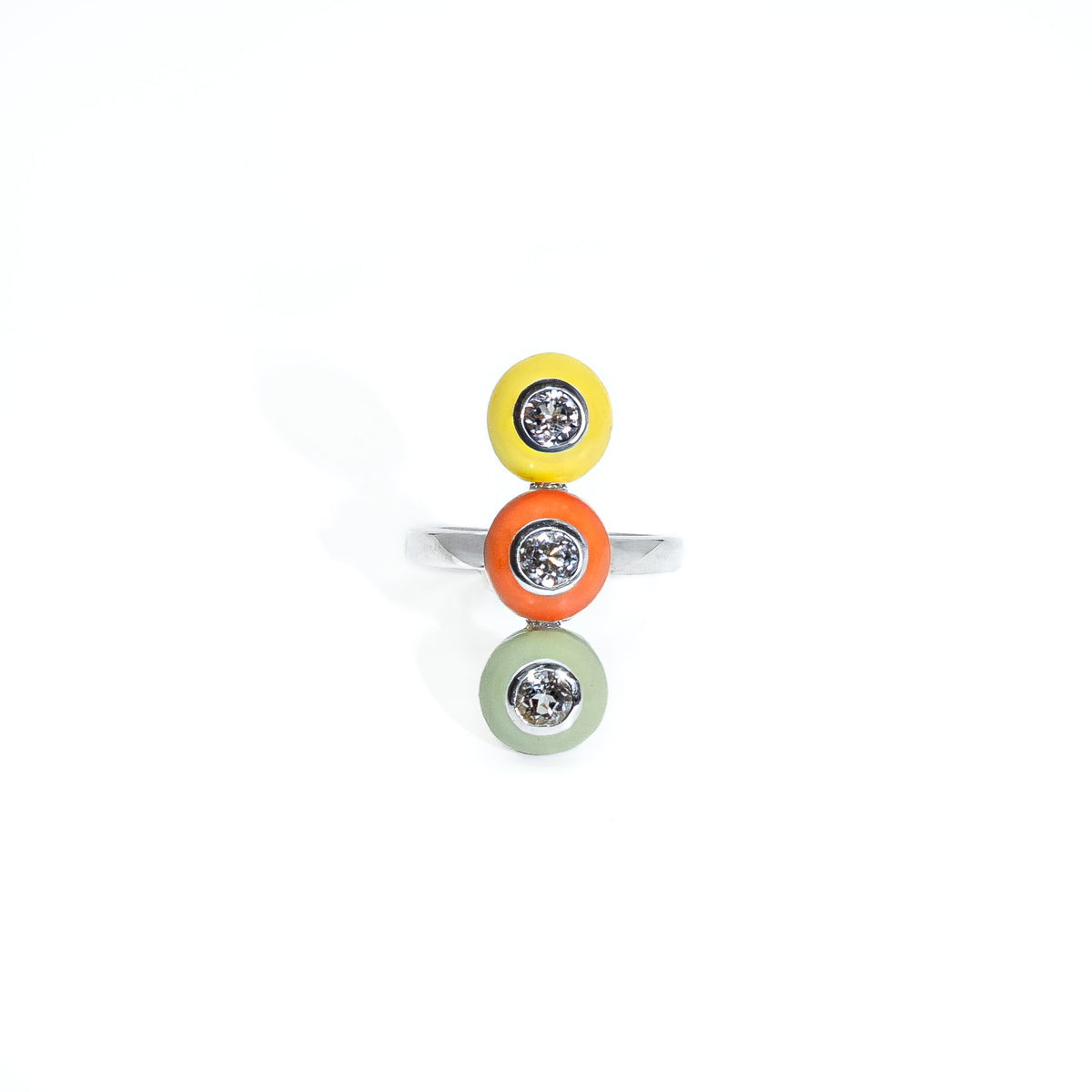 A silver ring featuring three stacked circular enamel bezels in yellow, orange, and light green, each set with a small white sapphire gemstone, on a plain white background.