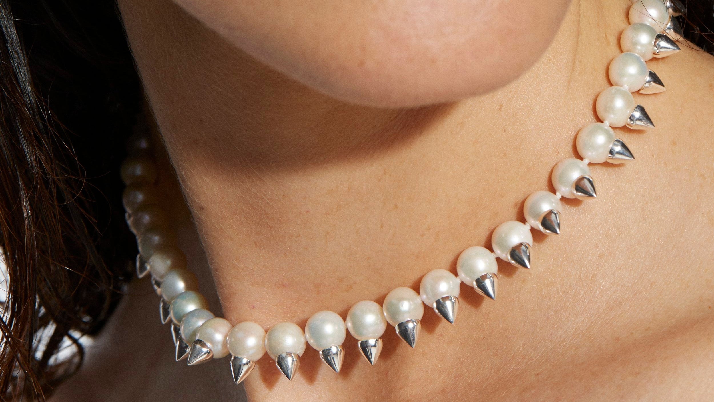 Pearl necklace with silver spike details worn by a person