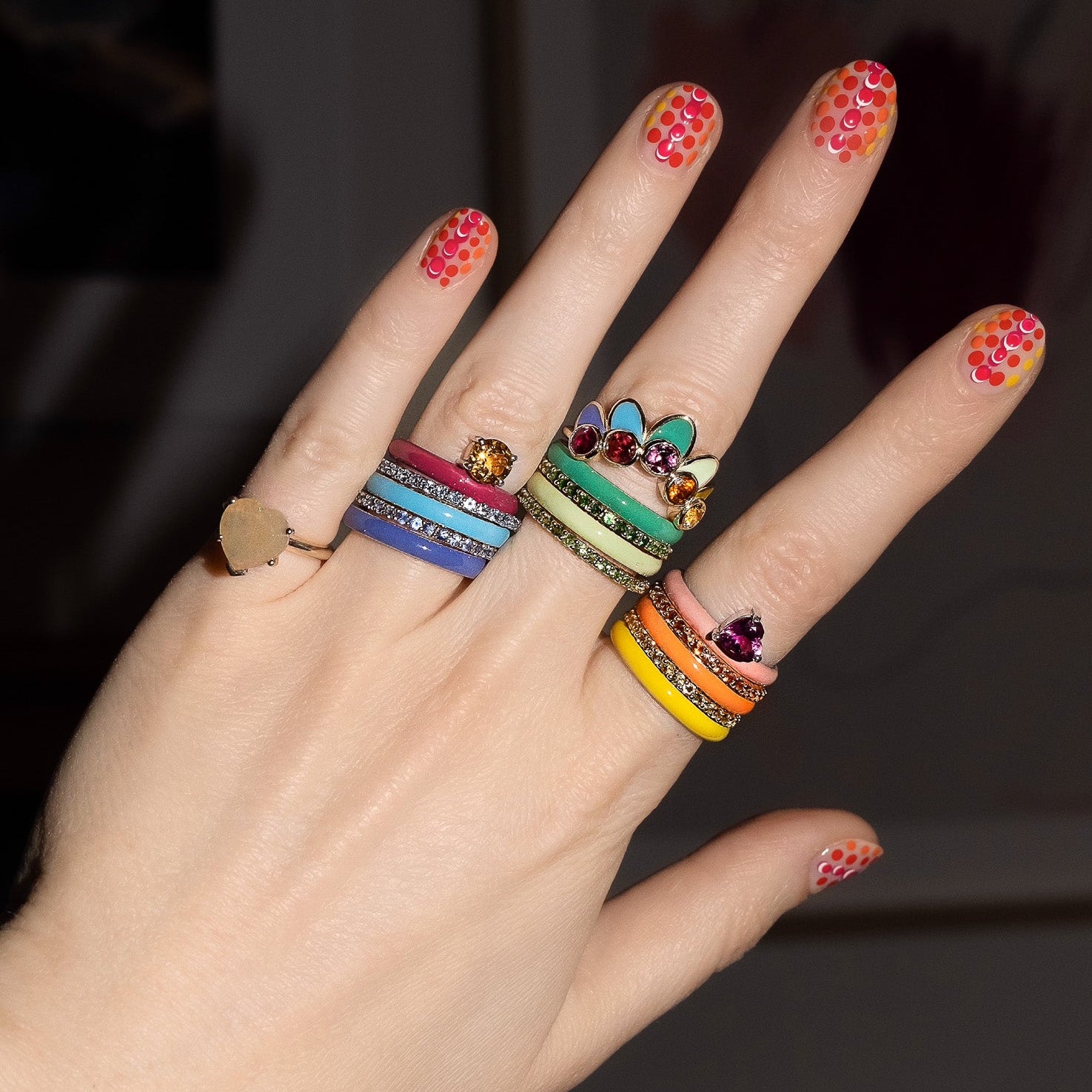 Hand wearing multiple colorful rings with a blurred background