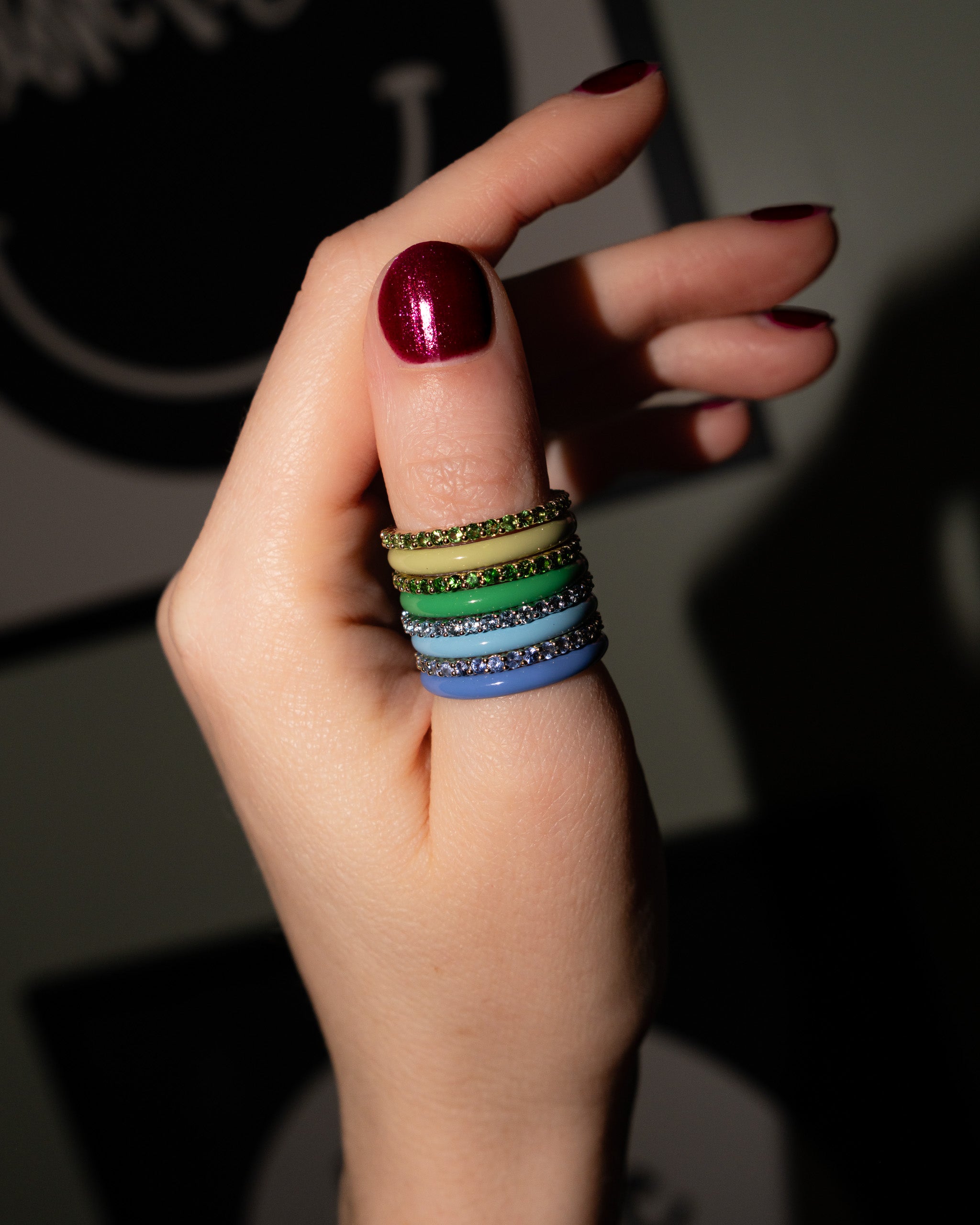 Blue and green enamel and pave stacking rings on a hand