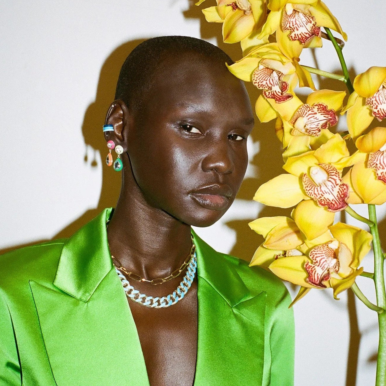 Person wearing a green outfit holding yellow flowers against a white background