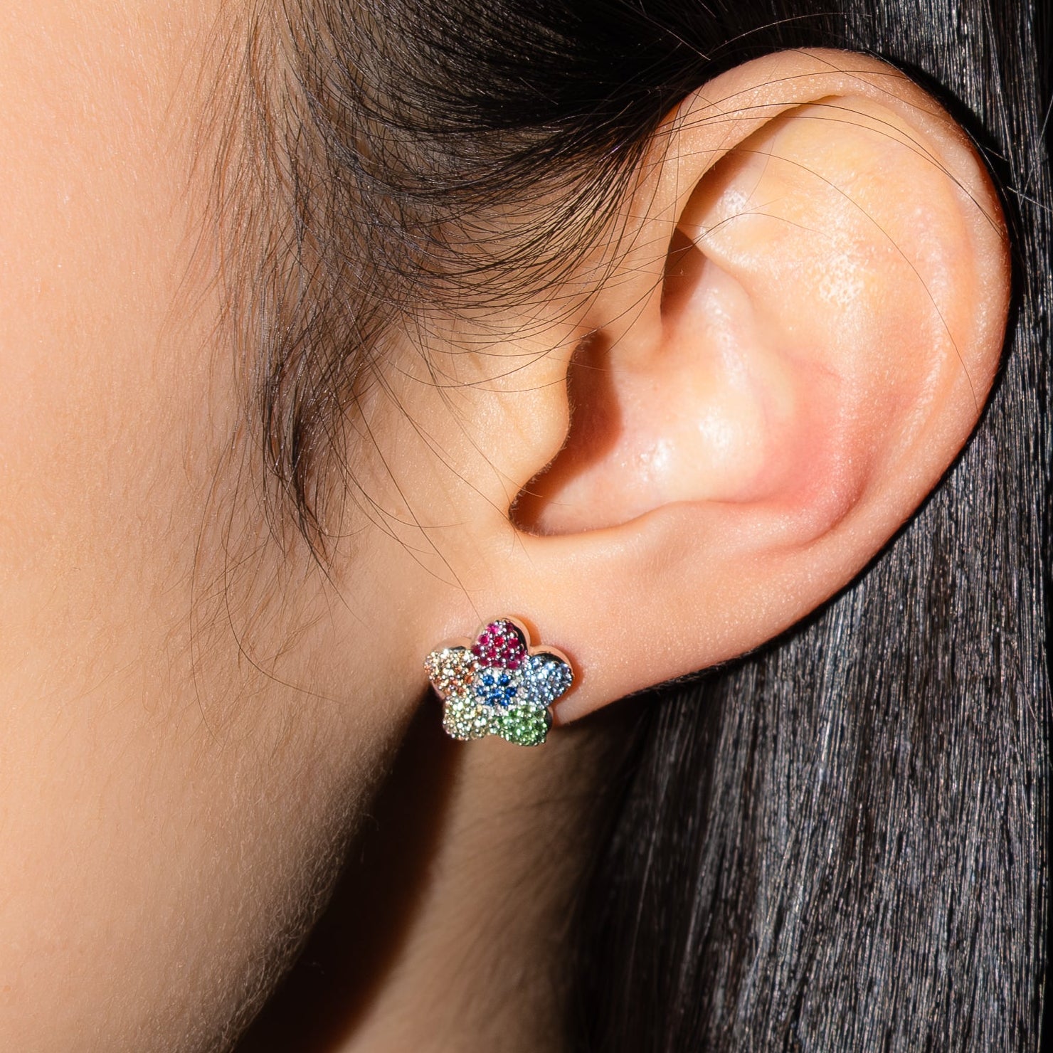 Close-up of an ear with a colorful earrings.