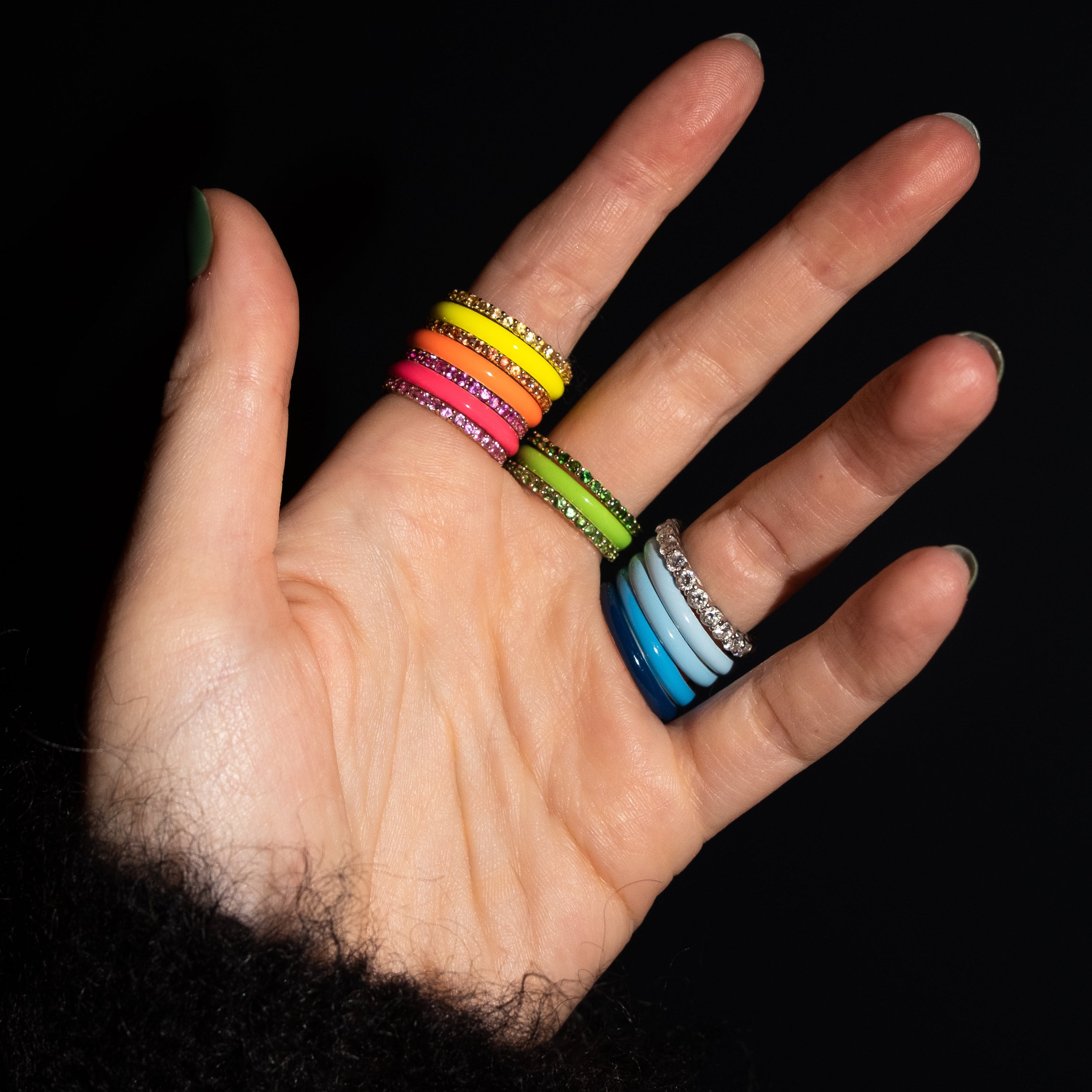 Hand wearing colorful bracelets on a black background