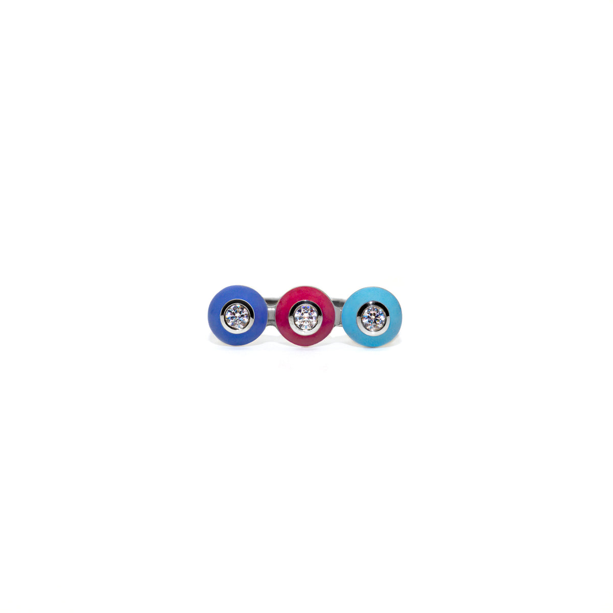 A silver-metal bar-style ring featuring three circular enamel bezels in blue, magenta, and light blue, each with a white sapphire gemstone in the center, shown on a plain white background.