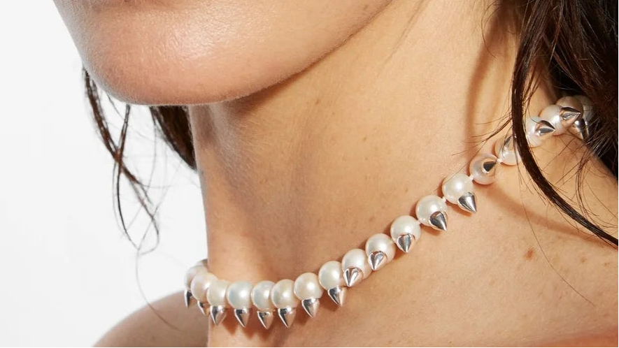 Close-up of a woman wearing a pearl necklace and earring on a white background