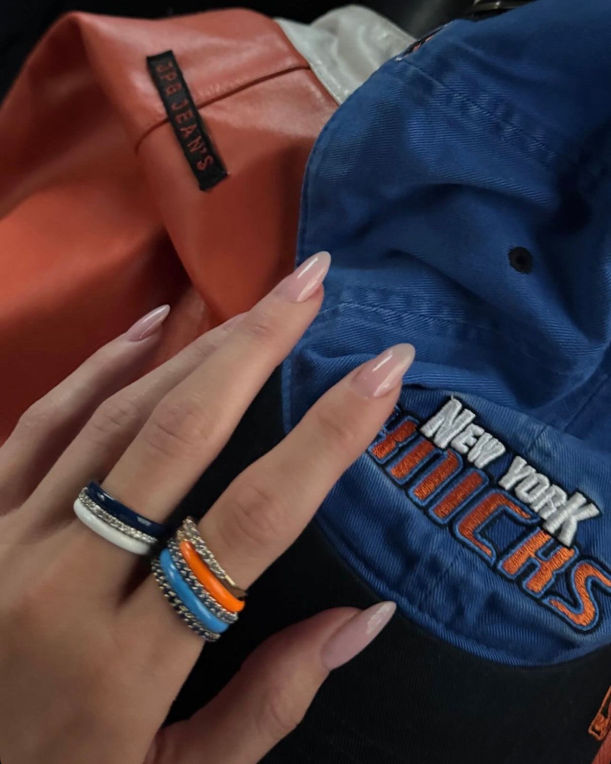 Kylie Jenner wearing orange-and-blue FRY POWERS POWERS PAVÉ rings with a Knicks cap and orange garment